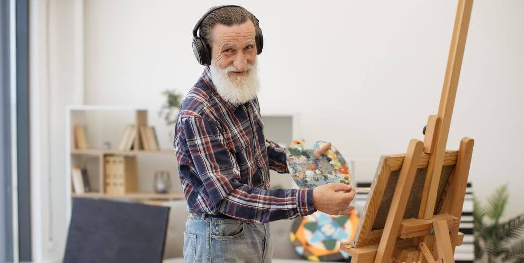 Elderly Man Smiling While Painting At Independent Living Facility