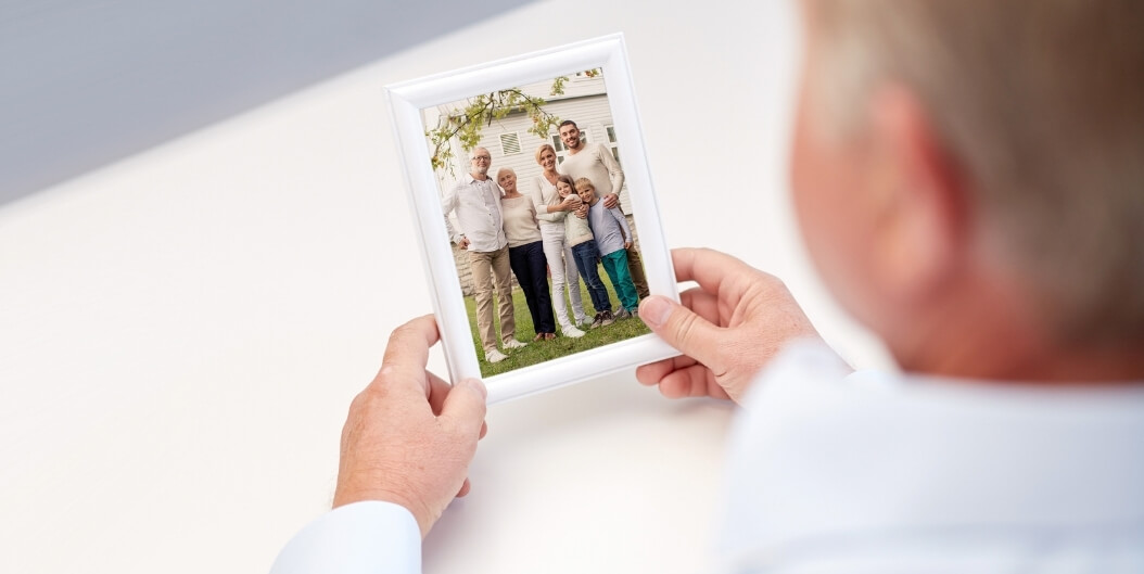 Elderly Man Holding Framed Family Photo in Independent Living