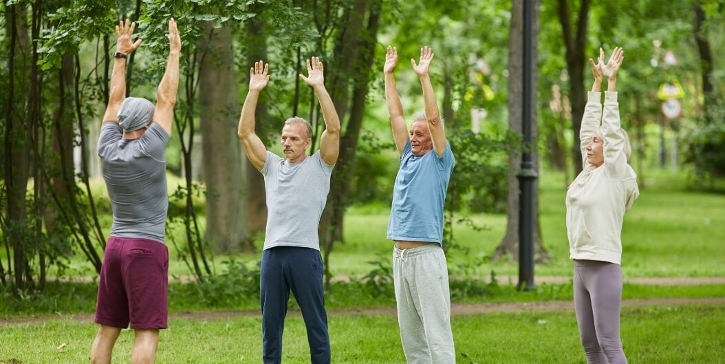 Group of Elderly Adults Stretching Together Outdoors at an Independent Living Facility