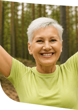 Happy Elderly Woman With Arms Raised in the Forest Near Independent Living