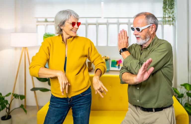 Playful Elderly Couple in Sunglasses Dancing in the Living Room at an Independent Living Facility