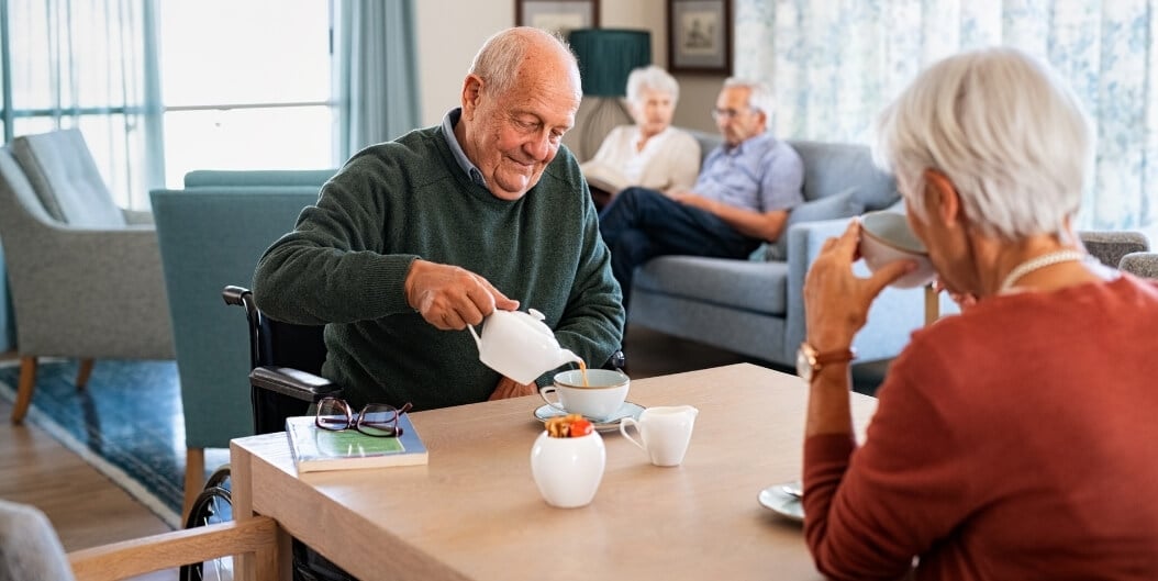 Elderly Man Pouring Tea for Resident at Independent Living Facility